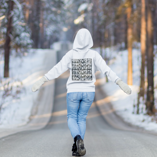 Woman wearing Empowered white hoodie walking on snowy road